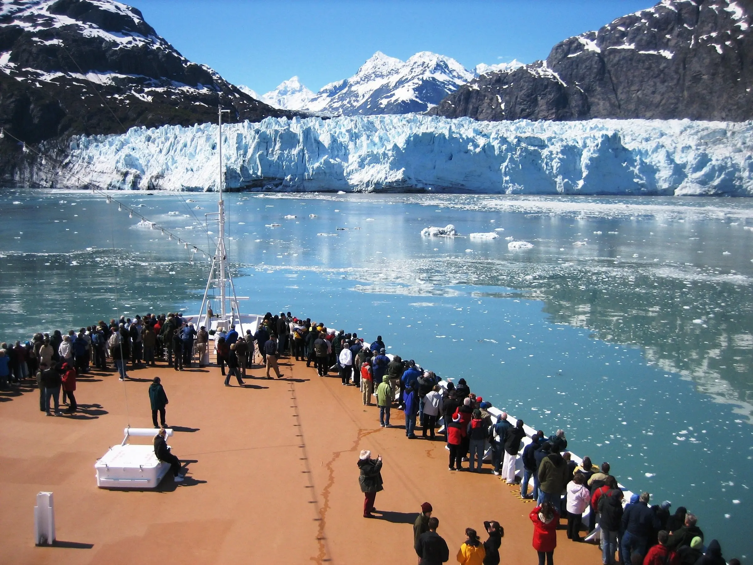 Cruise passengers on a ship's bow facing a tidewater glacier in Glacier Bay National Park